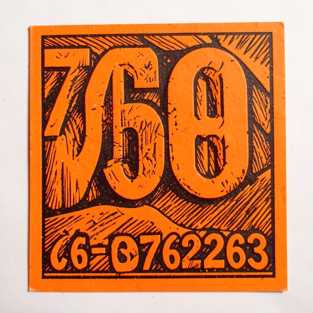 Carved linocut relief print of mathematical symbols and arrows arranged in a grid, terracotta and cream tones